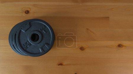 Powerful dumbbell plate with grip hole design on wooden background