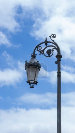 Lampadaire antique encadré par des nuages gonflants dans un paysage urbain nostalgique