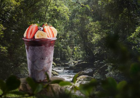 Photo for Brazilian acai cup topped with strawberry and banana, on a Amazon rainforest. - Royalty Free Image