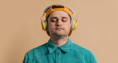 Téléchargez les photos : Stylish man in green shirt with headphones on brown background - en image libre de droit