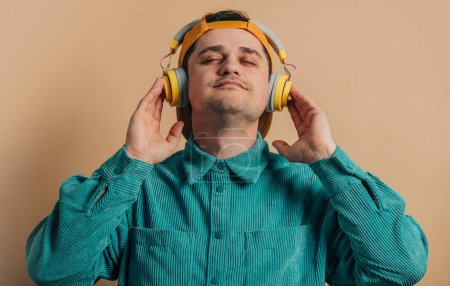 Téléchargez les photos : Stylish man in green shirt with headphones on brown background - en image libre de droit
