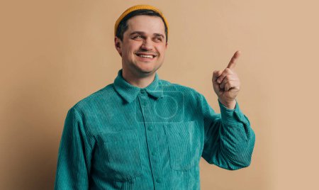 Téléchargez les photos : Stylish caucasian man in green shirt and yellow hat on brown background - en image libre de droit