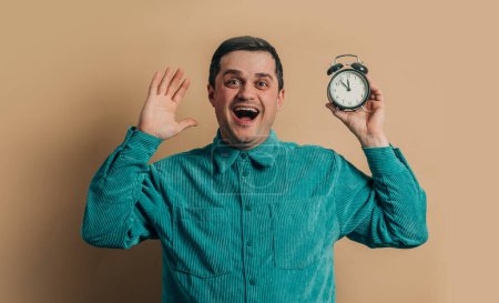 Téléchargez les photos : Surprised caucasian man in green shirt with vintage alarm clock on brown background - en image libre de droit