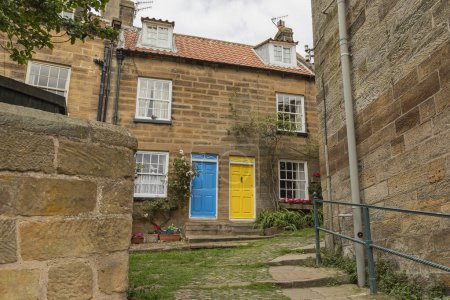 Looking up an alleyway at two houses with brightly coloured doors one yellow and one bright blue