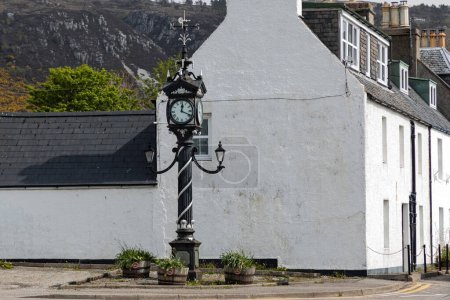Foto de Durness, Escocia, Reino Unido - 5 de mayo de 2023 - Reloj blanco y negro adornado en la esquina de una pequeña ciudad costera escocesa - Imagen libre de derechos