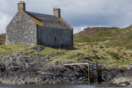 Téléchargez les photos : Ancien bâtiment en pierre grise à côté d'une jetée en métal sur une île reculée - en image libre de droit