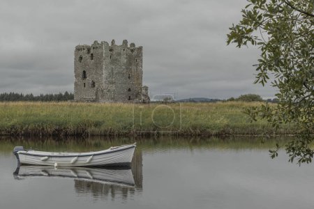 Photo for Looking across a lake at a derelict castle with a white rowing boat in the water - Royalty Free Image