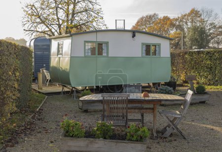 Klassischer alter grüner und cremefarbener Wohnwagen mit Esstisch im Freien