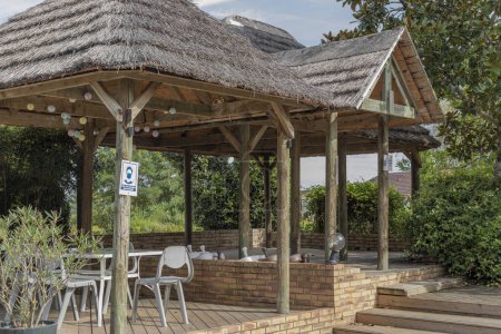 Outdoor covered area with a grass roof and some tables and chairs