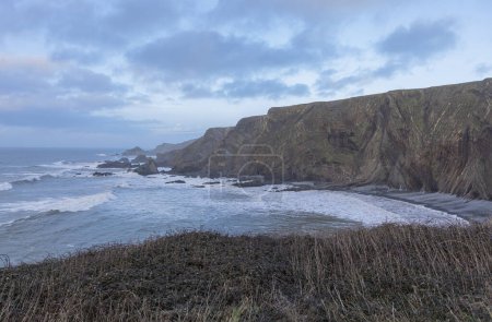 Foto de Moody paisaje marino de invierno con acantilados y olas y un cielo tormentoso áspero - Imagen libre de derechos
