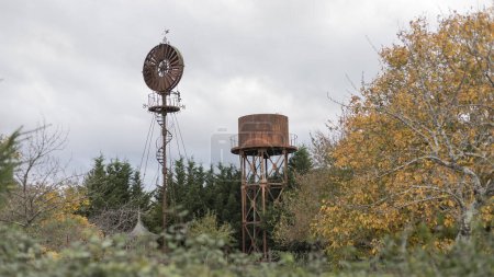 Rust coloured metal wind structure and water tower in a garden 