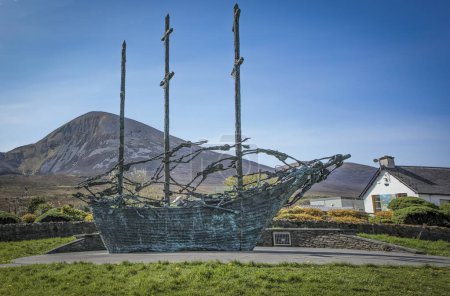 Photo for Murrisk, Demesne, Murrisk, County Mayo, Ireland - April 20th 2024 - Irish monument to the famine depicting close ups  of skeletons on a sailing ship set against the Craiogh Patrick mountain - Royalty Free Image