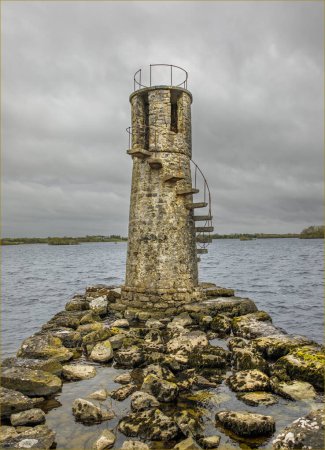 Watery and stoney lead up to a stone lighthouse positioned on the edge of a lake