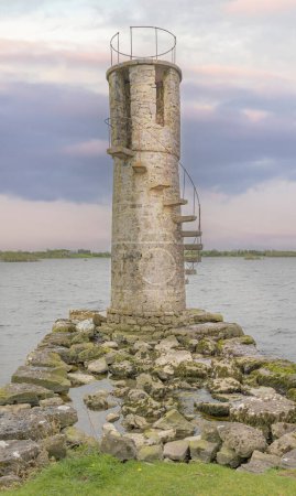 Close up of a inland lighthouse on the eadge of a Louch as the sun begins to set