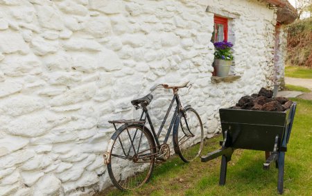 Altes Fahrrad und alte hölzerne Schubkarre gegen eine weiß gewaschene Wand