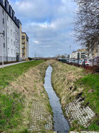 A narrow stream flows between city houses in the spring. High quality photo