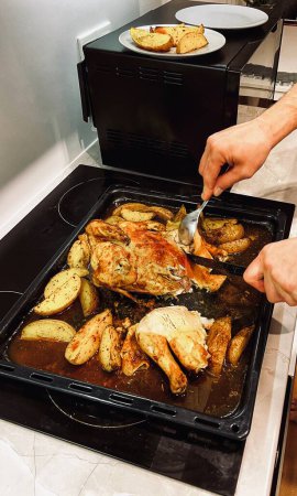 Las manos cortan el pollo cocido con las patatas con el cuchillo. Foto de alta calidad