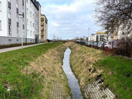 A narrow stream flows between city houses in the spring. High quality photo