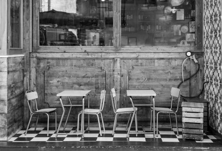 Foto de Mesas y sillas de metal vintage están en la ventana de un viejo café en un azulejo blanco y negro. Foto en blanco y negro - Imagen libre de derechos