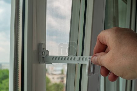 Photo for Master installed fixing limiter for opening a plastic window and checks its operation. Close-up of a hand checking the operation of window fittings. Home repairs. Installing window hardware. - Royalty Free Image