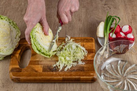 Photo for Hands of a woman chopping white cabbage with a kitchen knife on a cutting board. Preparing fresh vegan salad. Fresh vegetable salads are good for health. The concept of a healthy lifestyle. - Royalty Free Image