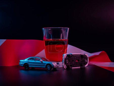 Téléchargez les photos : Mini accident de voiture. Alcool et une voiture jouet sur fond noir. Avertissement de conduite en état d'ébriété. - en image libre de droit