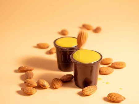 Vanilla pudding in a glass of chocolate on an orange background. Chocolate with vanilla pudding and nuts.