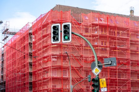 Photo for Red building with scaffolding and green traffic light. Restoration of an old building. - Royalty Free Image