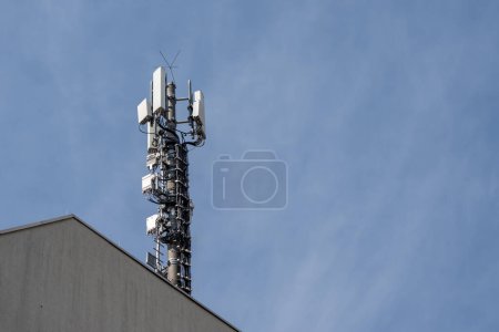 A tall tower with a lot of antennas on top of it. The sky is blue and there are some clouds