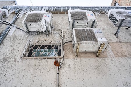 Foto de Riga, Letonia - 12 diciembre, 2022: Varias marcas de acondicionadores de aire montados en la pared están congelados y cubiertos de carámbanos. Vista inferior. - Imagen libre de derechos