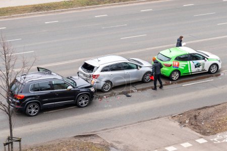 Foto de Riga, Letonia - 15 de febrero de 2023: Accidente de accidente automovilístico con tres coches en una calle de la ciudad. Un conductor se para cerca de coches destrozados y llena los documentos para el seguro. - Imagen libre de derechos