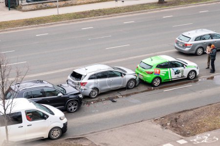 Foto de Riga, Letonia - 15 de febrero de 2023: Accidente de accidente automovilístico con tres coches en una calle de la ciudad. Un conductor se para cerca de coches destrozados y llena los documentos para el seguro. - Imagen libre de derechos