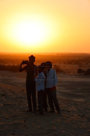 Foto de Chicos tomando selfie al atardecer en el desierto en la India - Imagen libre de derechos