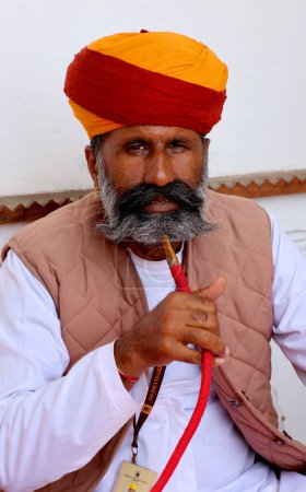 Foto de JODHPUR RAJASTHAN INDIA - 02 13 2023: Un viejo indio anciano pobre retrato sin identificar con una cara arrugada de color marrón oscuro y cabello blanco y una barba blanca, parece serio. Imagen emocional - Imagen libre de derechos