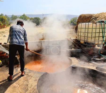 Téléchargez les photos : RURAL RAJASTHAN INDIA - 02 16 2023 : Homme travaillant dans une usine de canne à sucre bouillante - en image libre de droit