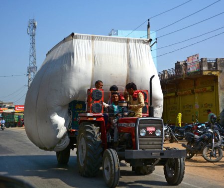 Foto de RURAL RAJASTHAN INDIA - 02 23 2023: Tractor lleva heno y se mueve por carretera. - Imagen libre de derechos