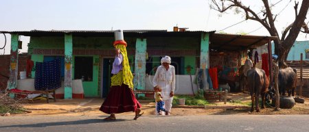 Téléchargez les photos : RURAL RAJASTHAN INDIA - 03 01 2023 : Rajasthani portant des pots d'eau dans la tête. Le pays compte 18 % de la population mondiale, mais seulement 4 % de ses ressources en eau - en image libre de droit