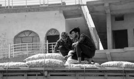 Téléchargez les photos : RAJASTHAN INDIA - 03 04 2023 : Des hommes fixent des sacs de pommes de terre sur le dessus d'un camion - en image libre de droit