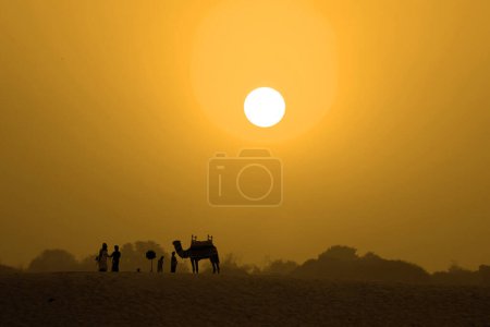 Photo for Silhouette of people and camel at sunrises over the eastern riverbank of the Ganges River near Varanasi, India. - Royalty Free Image