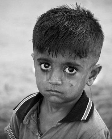 Foto de THAR DESERT JAISALMER RAJASTHAN INDIA - 02 13 2023: Retrato de niño en el desierto de Thar. Los niños tienen responsabilidades en el cuidado de sus hogares y familias; traen agua y muelen grano para la comida. - Imagen libre de derechos