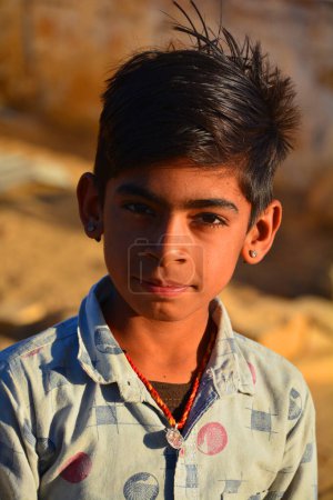 Téléchargez les photos : THAR DESERT JAISALMER RAJASTHAN INDIA - 02 13 2023 : Portrait d'enfant dans le désert de Thar. Les enfants ont la responsabilité de prendre soin de leur maison et de leur famille ; ils vont chercher de l'eau et broient du grain pour se nourrir.. - en image libre de droit