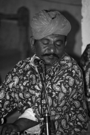 Photo for THAR DESERT RAJASTHAN INDIA - 02 17 2023: Local artist in traditional costume playing traditional desert musical instrument - Royalty Free Image