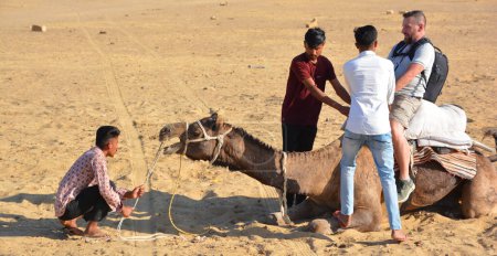 Photo for Tourist riding a camel for tourists for camel ride at Thar desert, Rajasthan, India. Camels, Camelus dromedarius, are large desert animals who carry tourists on their backs. - Royalty Free Image