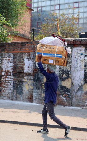 Foto de DELHI INDIA - 02 12 2023: El hombre del pueblo lleva sus cosas en la cabeza y regresa a casa - Imagen libre de derechos