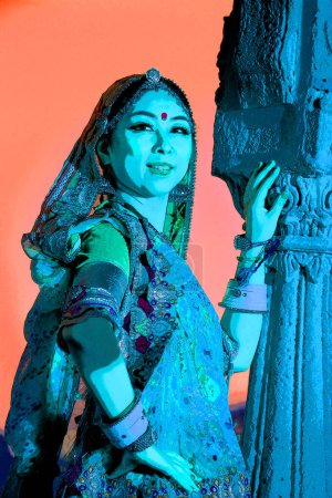 Foto de JAISALMER INDIA - 02 13 23: Ilustración de una hermosa joven india vestida con ropa tradicional con maquillaje nupcial y joyas orientales. - Imagen libre de derechos