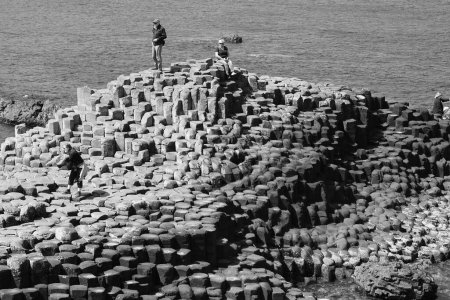 Photo for COUNTY ANTRIM 06 03 2023: People visiting the Giant's Causeway is an area of about 40,000 interlocking basalt columns, the result of an ancient volcanic fissure eruption. - Royalty Free Image