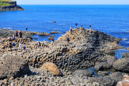 Photo for COUNTY ANTRIM 06 03 2023: People visiting the Giant's Causeway is an area of about 40,000 interlocking basalt columns, the result of an ancient volcanic fissure eruption. - Royalty Free Image