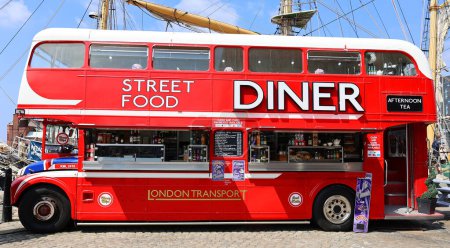 Photo for LIVERPOOL UNITED KINGDOM 06 07 2023: Red food double decker bus offering street food in Albert Dock with tables and a red telephone - Royalty Free Image