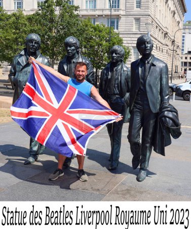 Foto de LIVERPOOL REINO UNIDO 06 07 20: Hombre con bandera británica frente a la estatua de los Beatles en el paseo marítimo de Liverpool en 2015. Donado por el famoso Cavern Club - Imagen libre de derechos