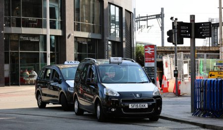 Foto de CARDIFF WALES REINO UNIDO 06 17 23: Cardiff Los taxis son negros con un capó blanco o son 'vehículos tipo taxi de Londres' que muestran una señal de techo que está iluminada cuando está disponible - Imagen libre de derechos